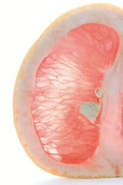 Nahaufnahme eines Querschnitts einer CitroPlus® 1200 forte (Bio)-Pomelo von gse.organic.supplements mit dicker gelber Schale und durchscheinendem rosafarbenem Fruchtfleisch, das reich an Polyphenolen ist, mit saftigen Segmenten und etwas weißem Mark.